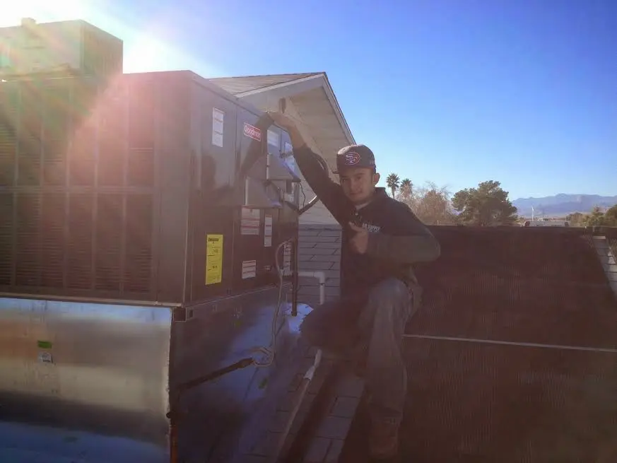 HVAC technician performing Heat Pump Repair on a rooftop unit in Wilmer